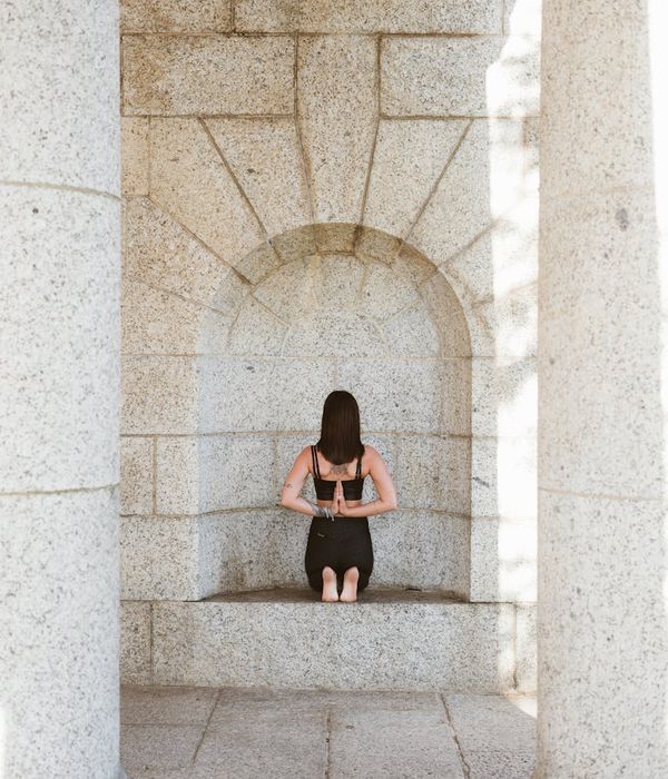 Woman in a calm, focused yoga pose against a dark background.